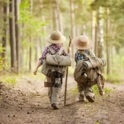 Deux enfants dans un forêt avec du matériel pour camper.