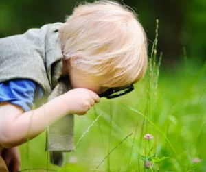 Un enfant qui observe à la loupe la nature.